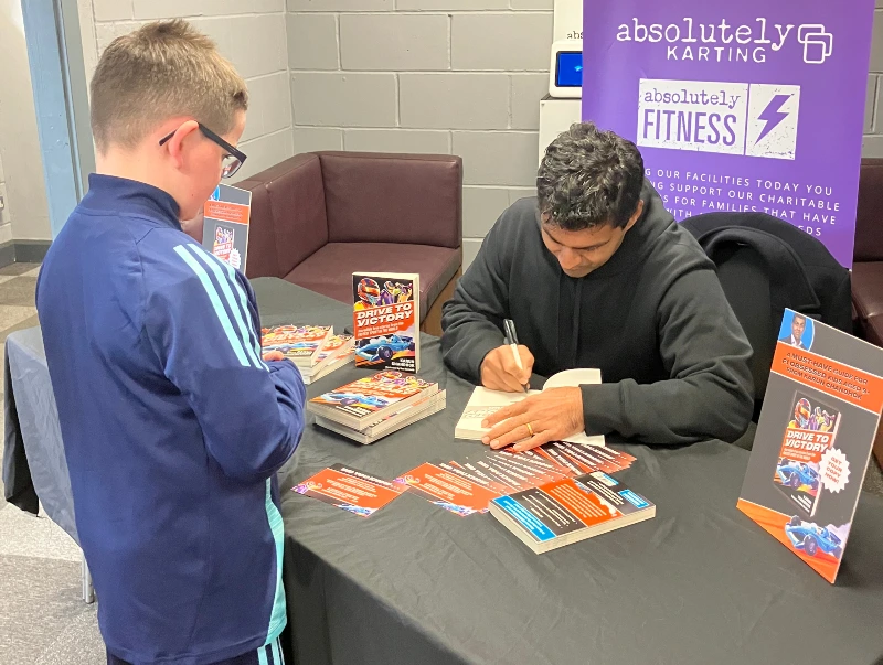 Karun Chandhok signing a copy of his book for a young fan.