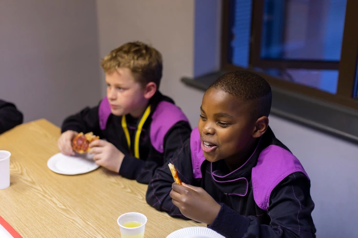 Two children eating pizza at a party.