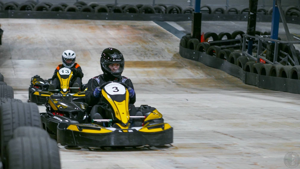 Two people in go karts going down a straight.