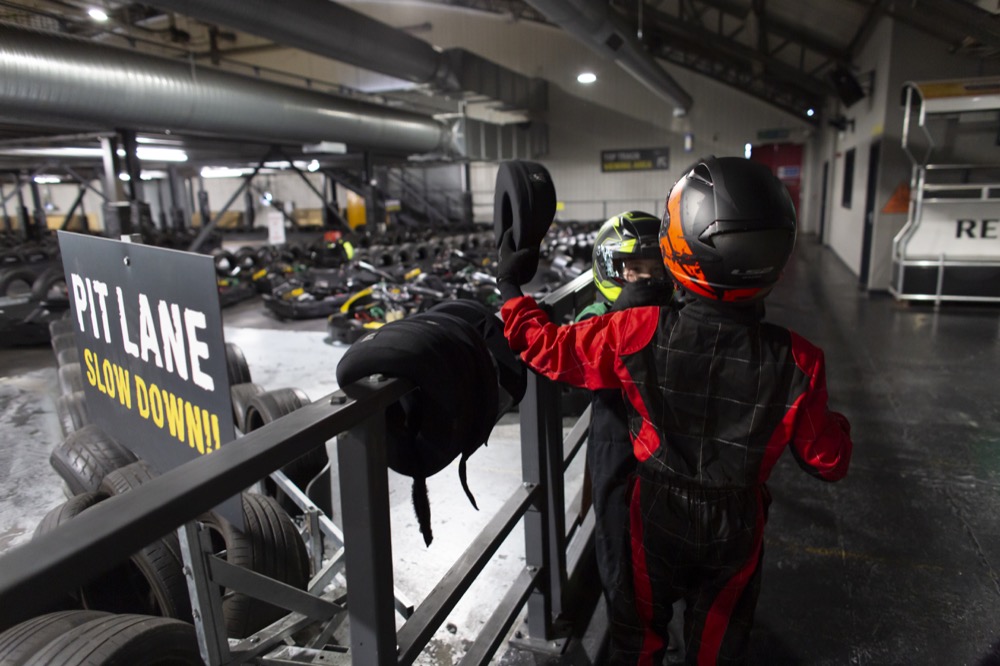 Two children waiting by the race track to getting in their karts