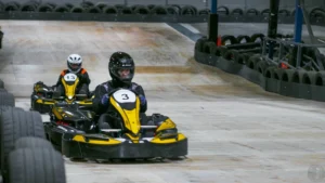 Two people in go karts going down a straight.